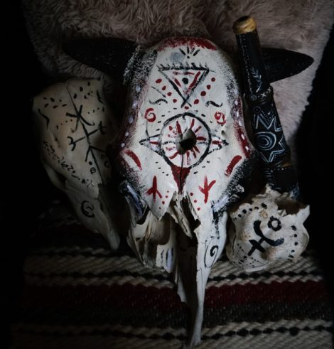 Bone magick: a bull skull with magical symbols and sigills on carpet for ritual use. 